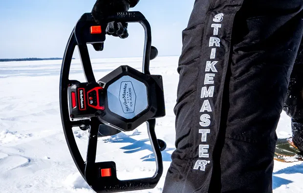 StrikeMaster ice auger cutting through thick ice on frozen lake with ice fishing angler